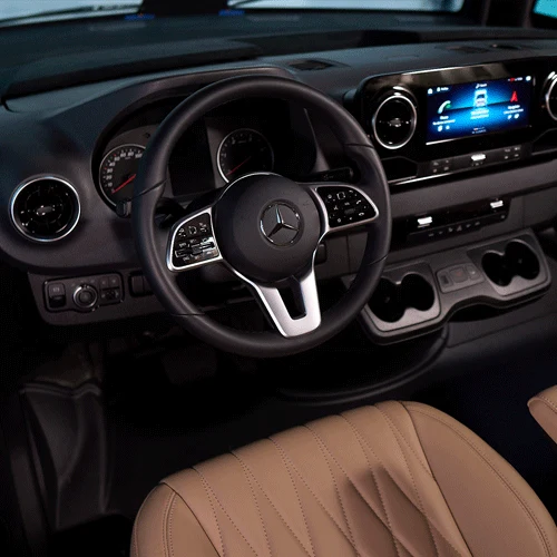 Mercedes-Benz steering wheel, digital display and tan leather seat in the HIP Campers 4Family cab